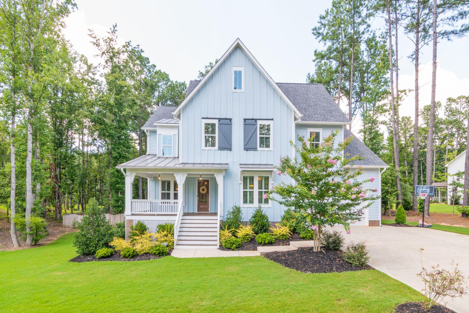 Two-story white residential house set behind mature trees